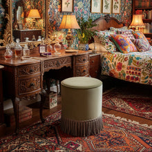Load image into Gallery viewer, Beige velvet ottoman with fringe on an eclectic background